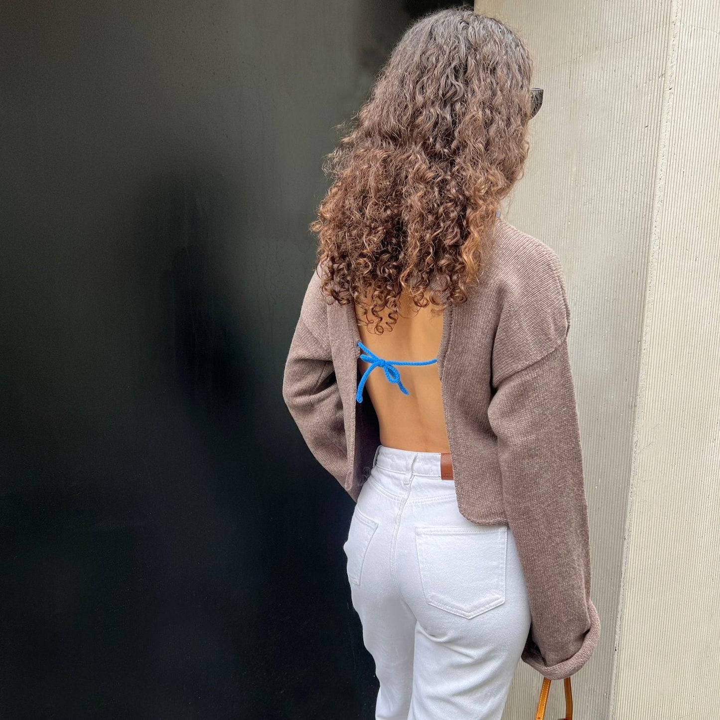 givéh knitwear handmade by female artisans in iran using only natural and recycled fibres. contemporary knitwear for cool people. taupe sweater with open back and wide sleeves. blue details. 100% merino wool. fall 2025 collection.