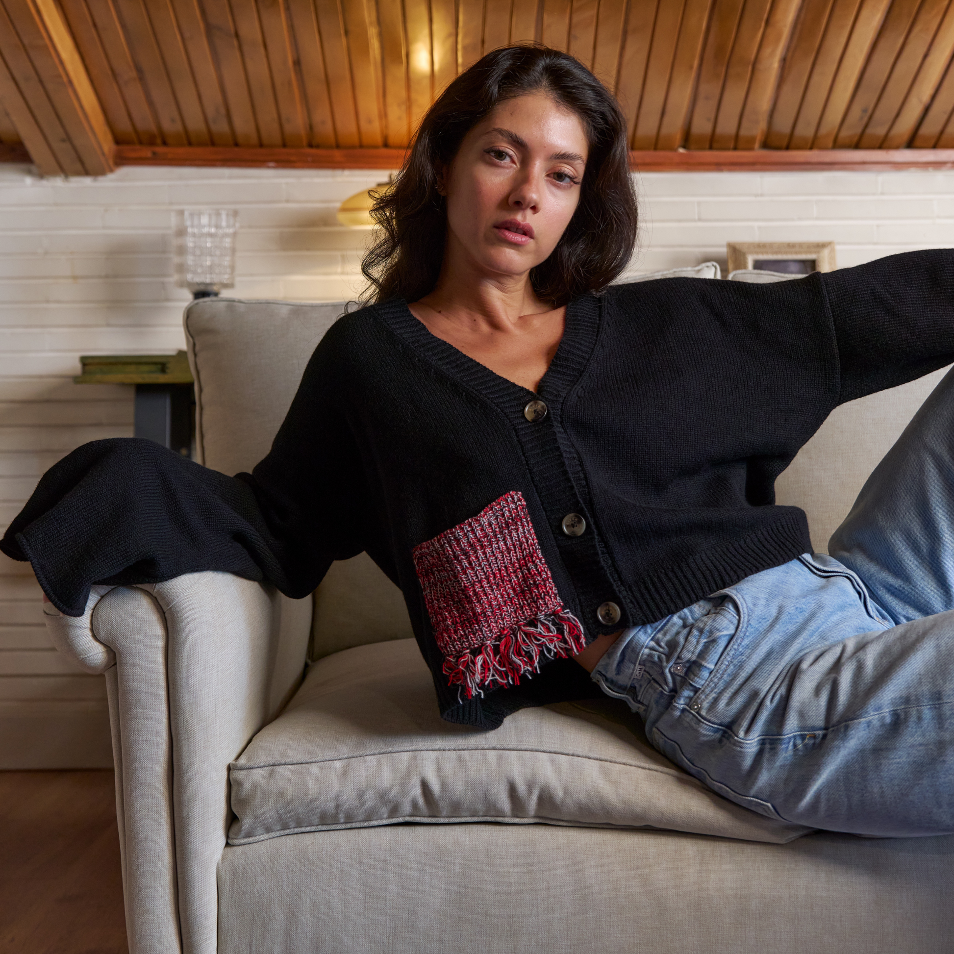 givéh knitwear handmade by female artisans in iran using only natural and recycled fibres. contemporary knitwear for cool people. black cardigan with red/black gradient fringe pocket. 3 natural horn buttons. 100% merino wool. fall 2025 collection.