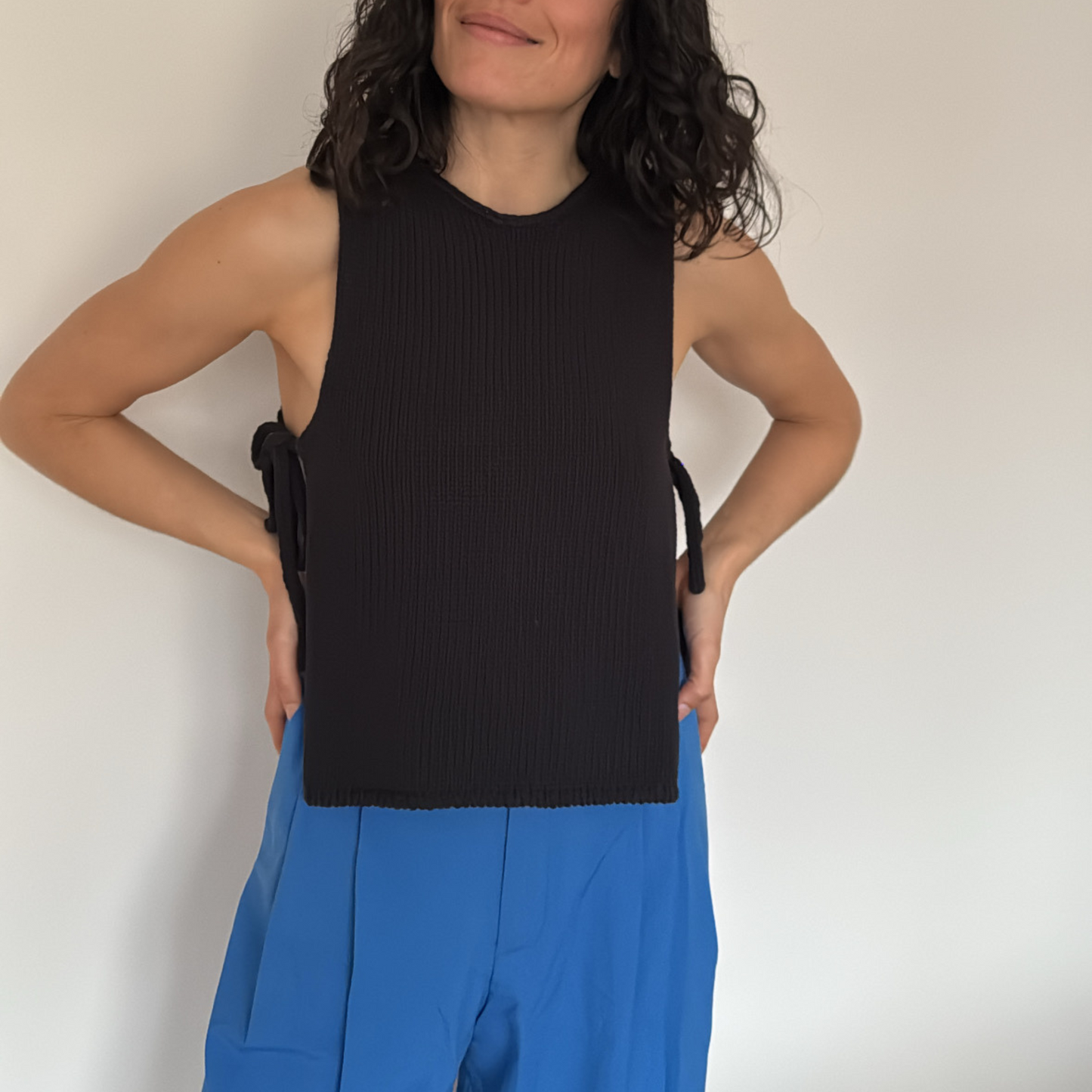 givéh knitwear handmade by female artisans in iran using only natural and recycled fibres. contemporary knitwear for cool people. black tie top, black open side top with tie closure and hand crocheted edges made out of cotton and recycled polyamide yarn. spring summer 2025 collection.