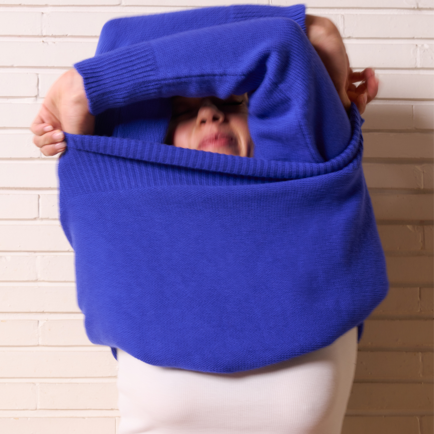 Person wearing a large blue sweater over their head against a beige wall.
givéh knitwear handmade by female artisans in iran using only natural and recycled fibres. contemporary knitwear for cool people. blue unisex crewneck sweater. 100% merino wool. fall 2025 collection.