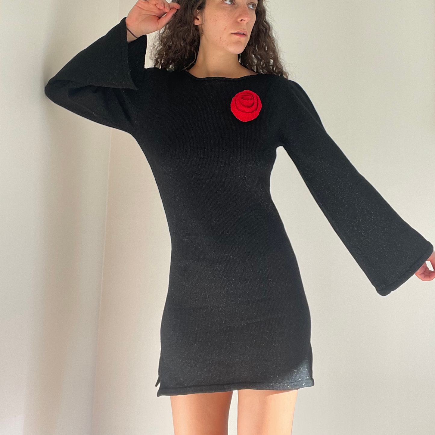 givéh knitwear handmade by female artisans in iran using only natural and recycled fibres. contemporary knitwear for cool people. black dress with red hand crocheted flower. made of merino wool. fall 2025 collection.
