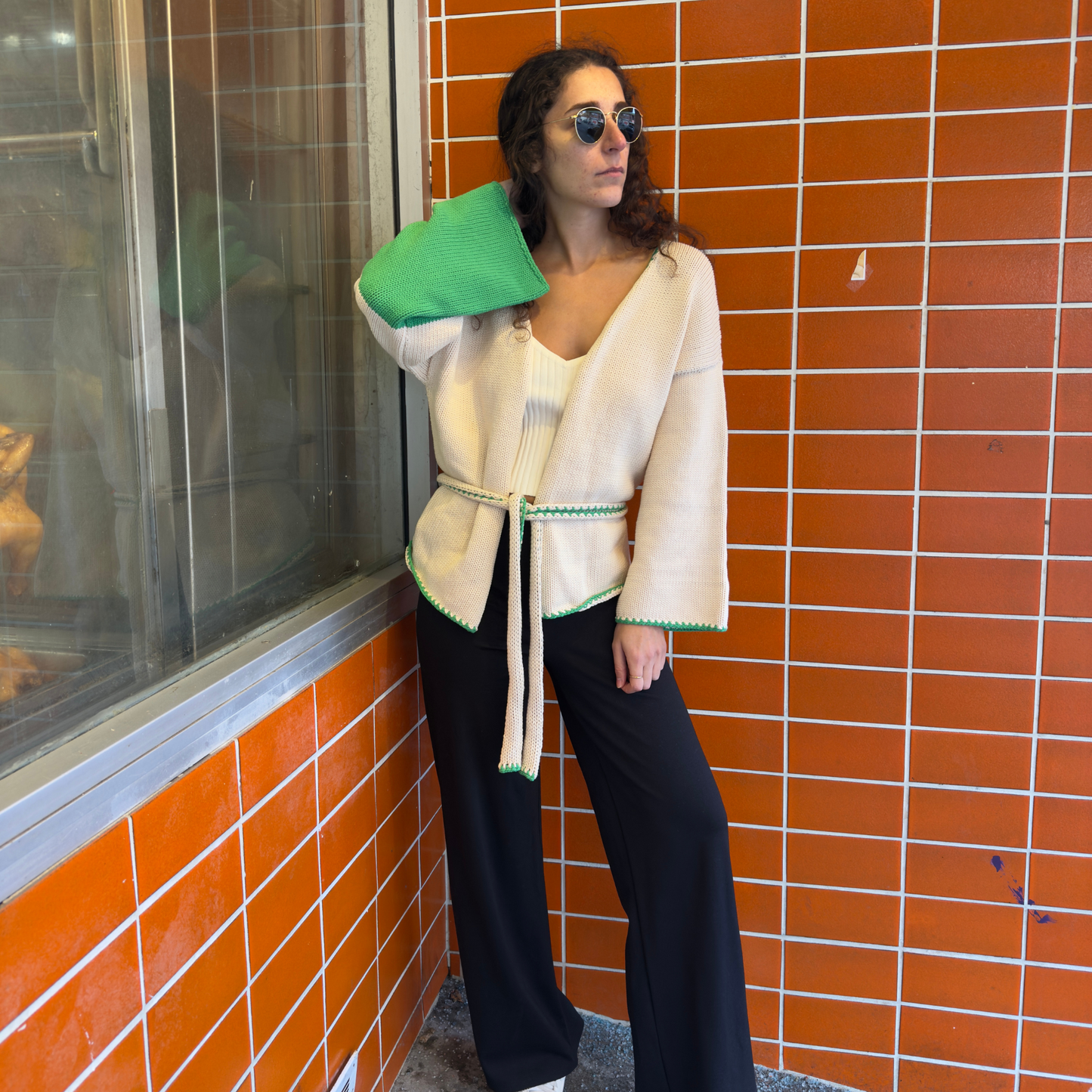givéh knitwear handmade by female artisans in iran using only natural and recycled fibres. contemporary knitwear for cool people. cream the cardi, cream and green knit cardigan with belt made of cotton and recycled polyamide yarn. spring summer 2025 collection.