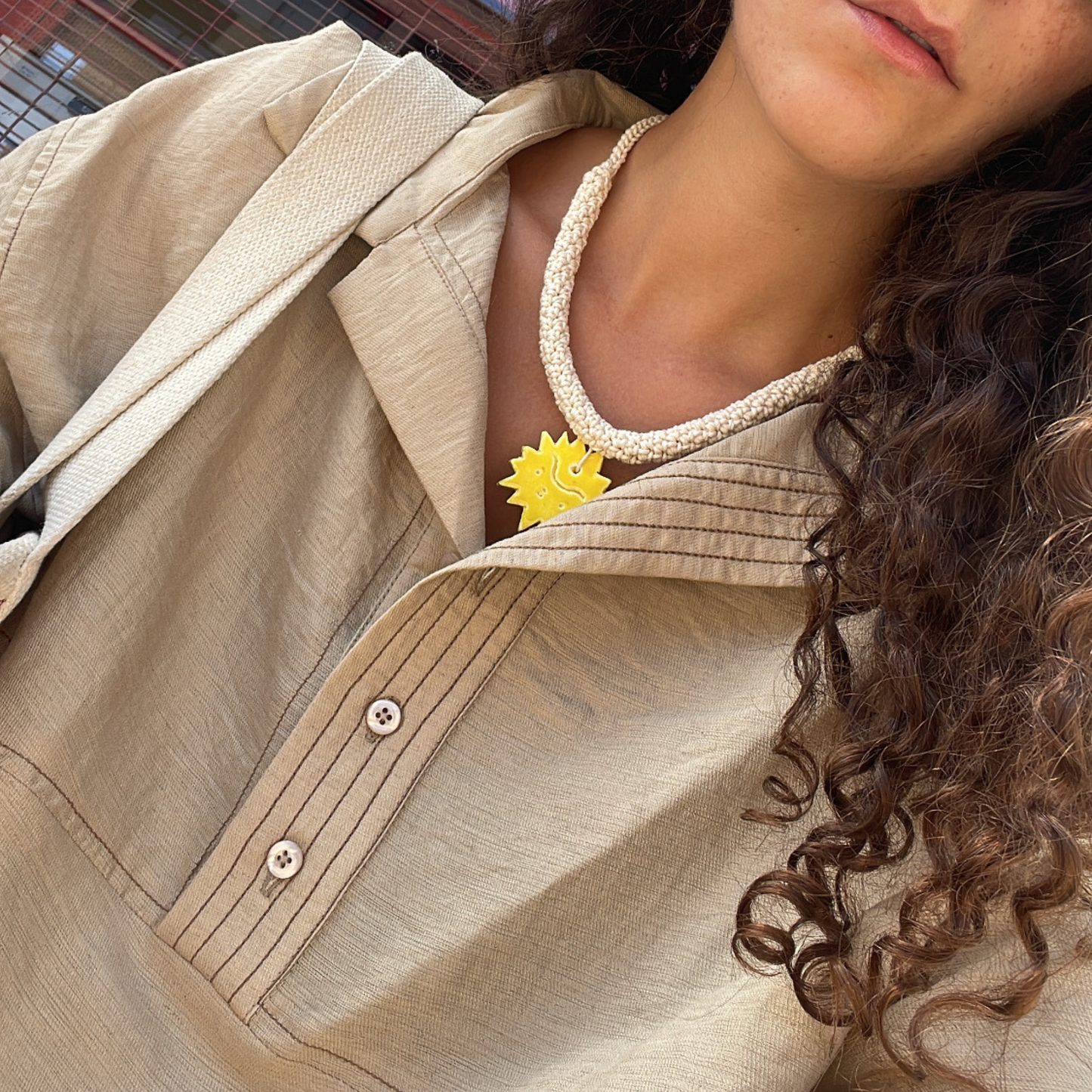 givéh knitwear handmade by female artisans in iran. aftab hand crocheted undyed cotton necklace with handmade clay ceramic pendant in the shape of the sun.