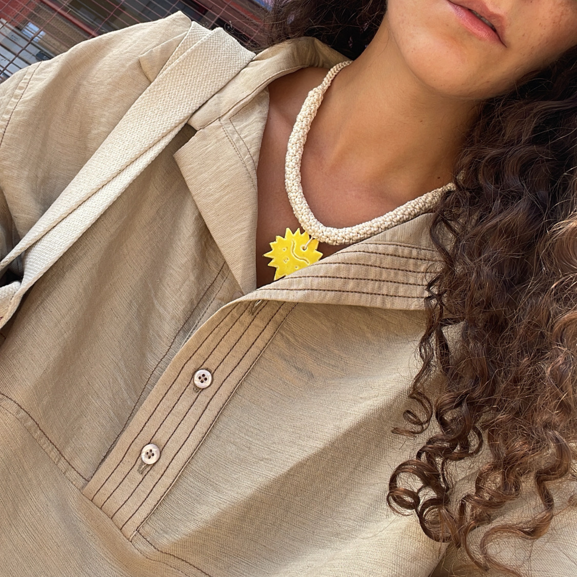 givéh knitwear handmade by female artisans in iran. aftab hand crocheted undyed cotton necklace with handmade clay ceramic pendant in the shape of the sun.