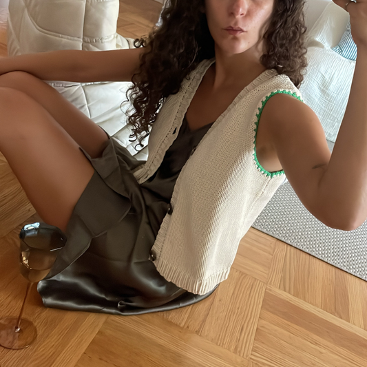 givéh knitwear handmade by female artisans in iran using only natural and recycled fibres. contemporary knitwear for cool people. cream vesty vest, cream and green knit vest with three natural horn buttons, made of cotton and recycled polyamide yarn, handcrocheted edges. spring summer 2025 collection.