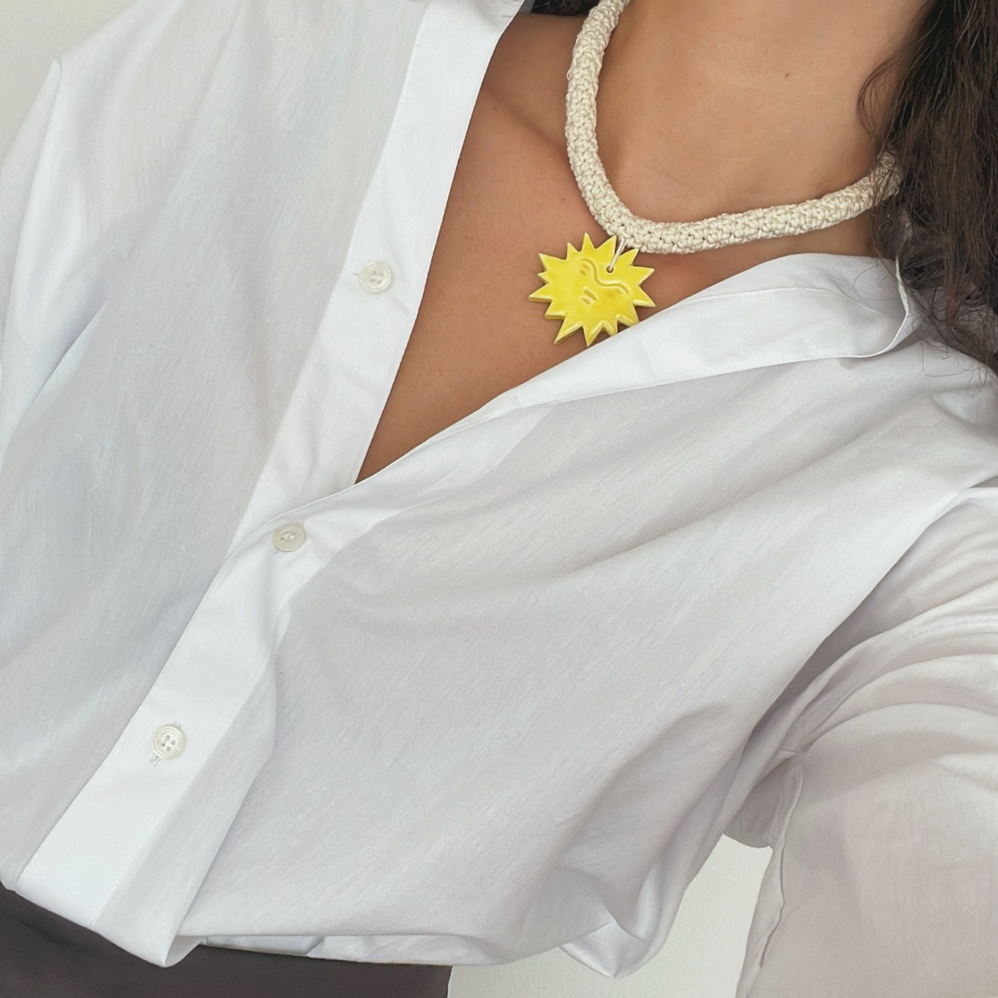 givéh knitwear handmade by female artisans in iran. aftab hand crocheted undyed cotton necklace with handmade clay ceramic pendant in the shape of the sun.