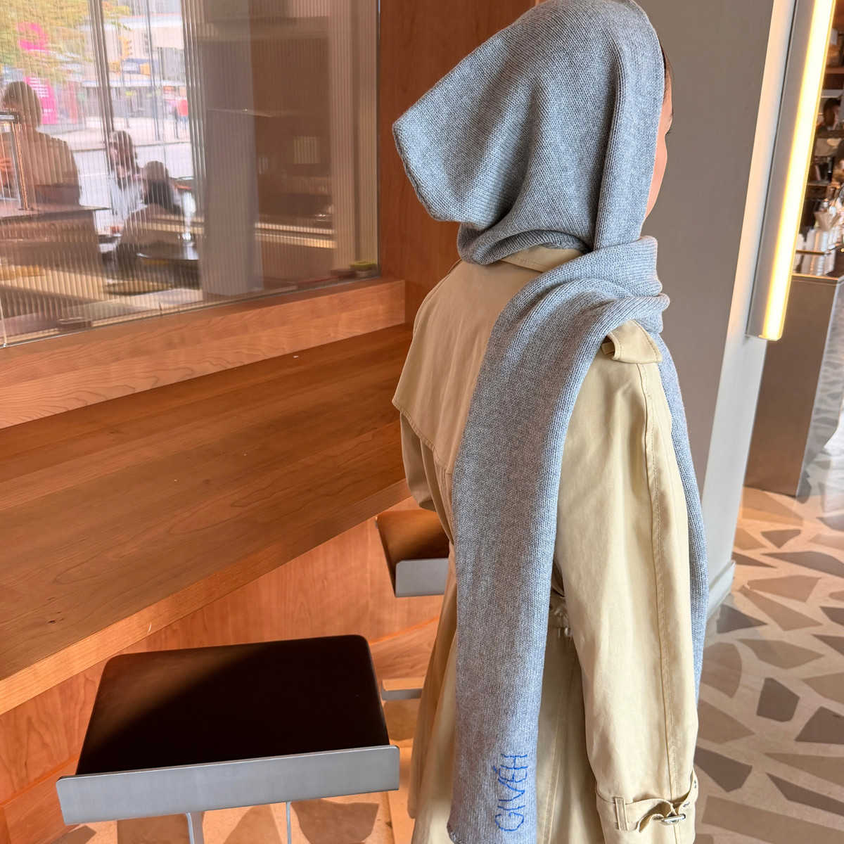 Givéh handmade merino wool cashmere-blend hooded scarf by female artisans in Iran, hand embroidered detail in grey, shown worn on model