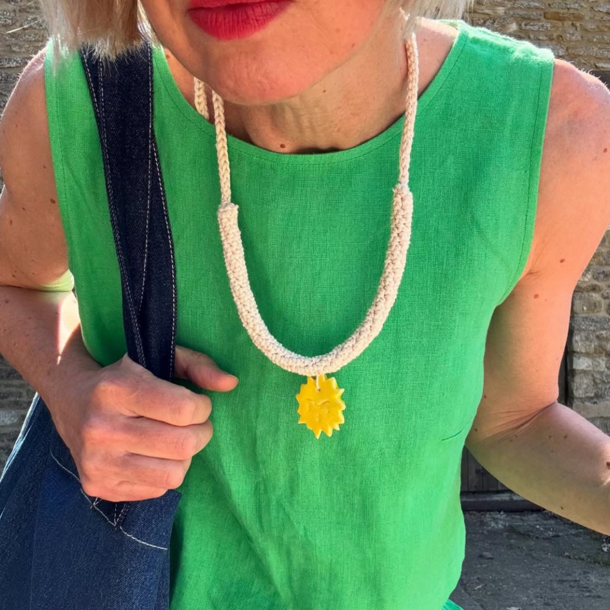 givéh knitwear handmade by female artisans in iran. aftab hand crocheted undyed cotton necklace with handmade clay ceramic pendant in the shape of the sun.