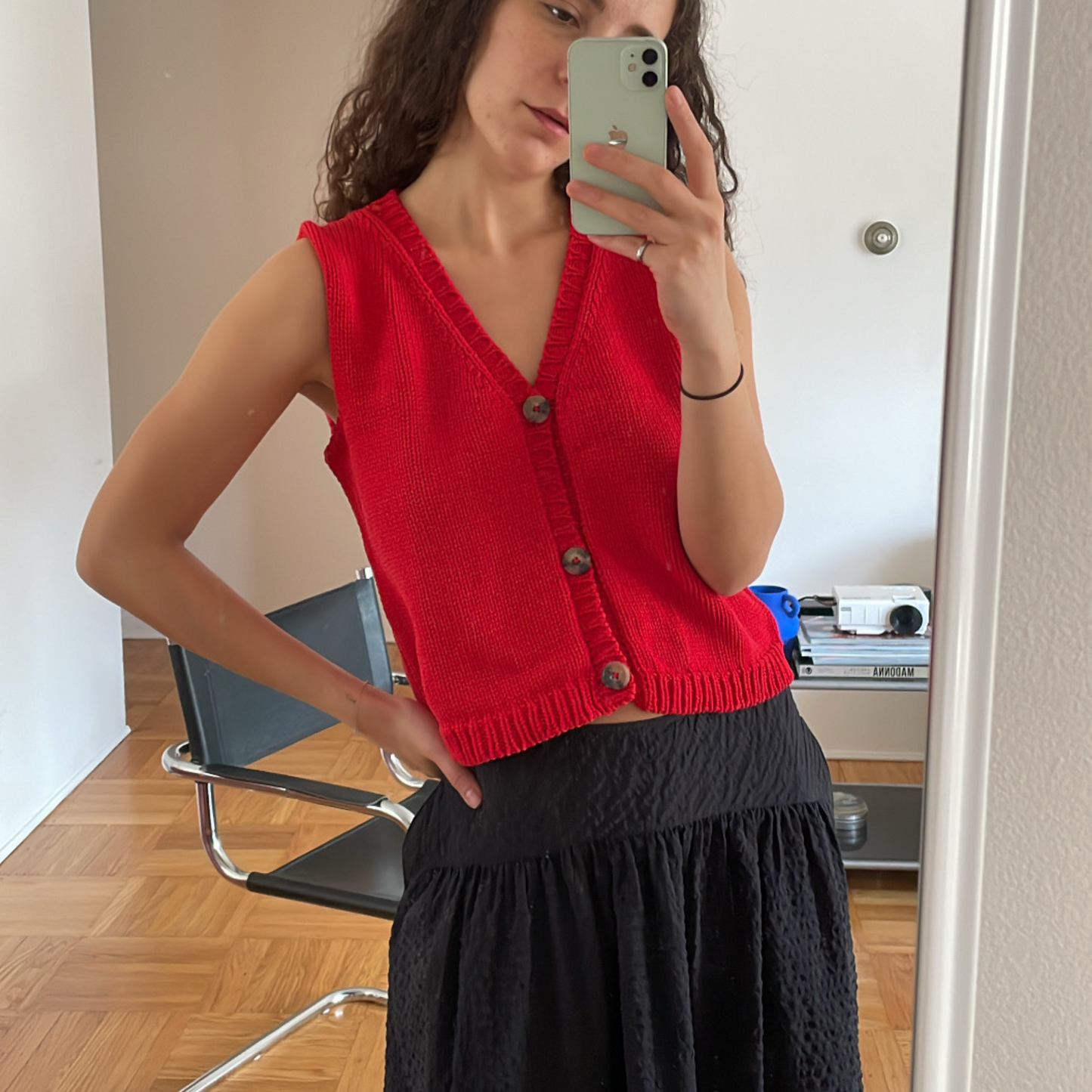 givéh knitwear handmade by female artisans in iran using only natural and recycled fibres. contemporary knitwear for cool people. red vesty vest, red knit vest with three natural horn buttons, made of cotton and recycled polyamide yarn, handcrocheted edges. spring summer 2025 collection.