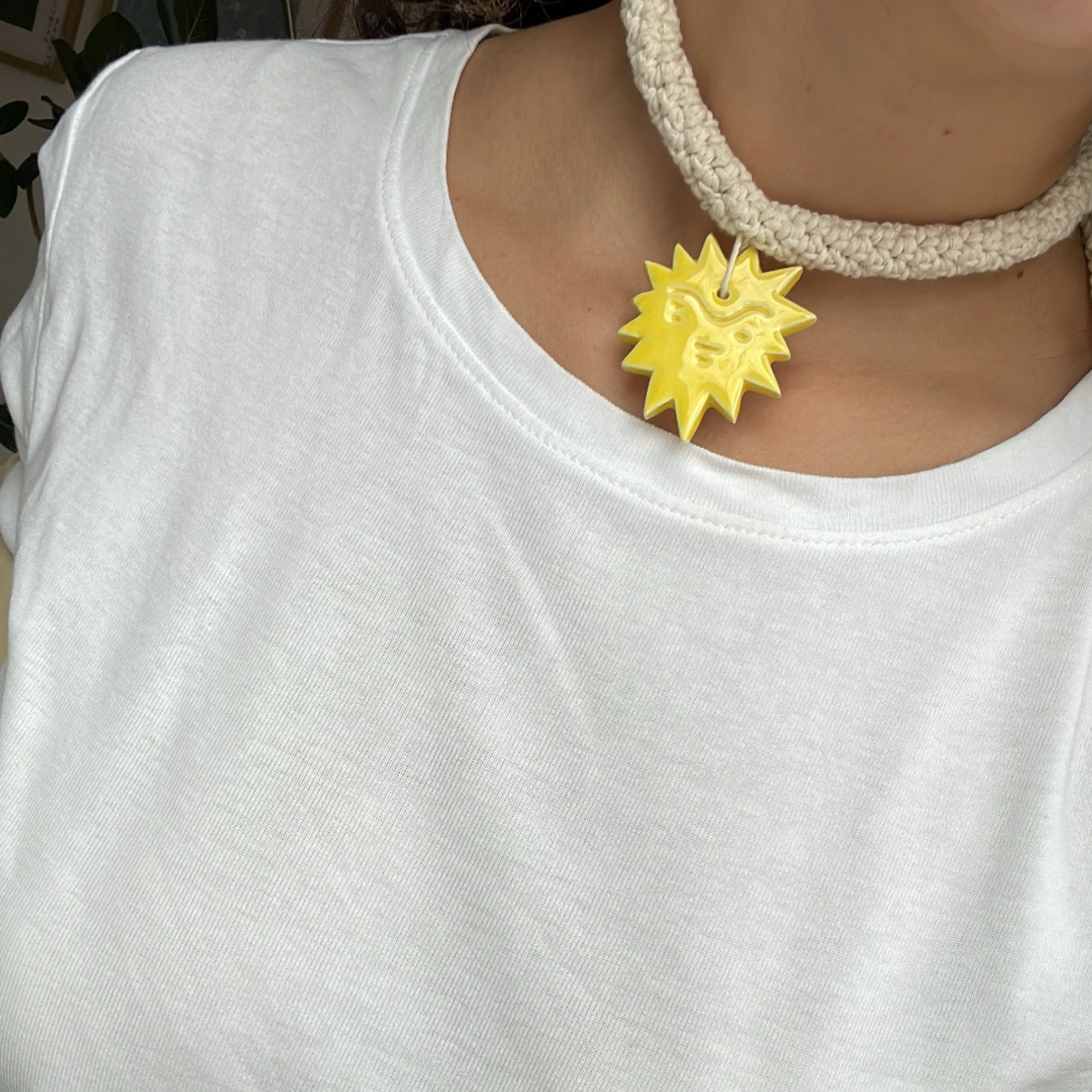 givéh knitwear handmade by female artisans in iran. aftab hand crocheted undyed cotton necklace with handmade clay ceramic pendant in the shape of the sun.