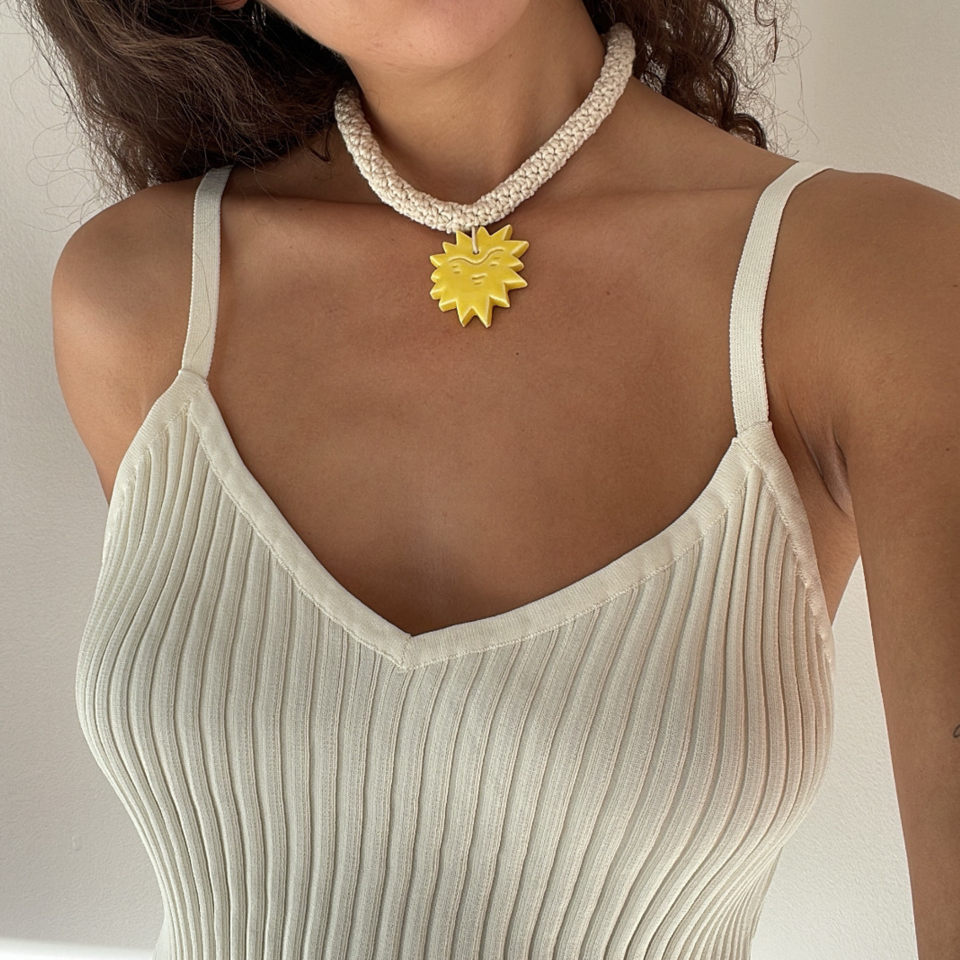 givéh knitwear handmade by female artisans in iran. aftab hand crocheted undyed cotton necklace with handmade clay ceramic pendant in the shape of the sun.
