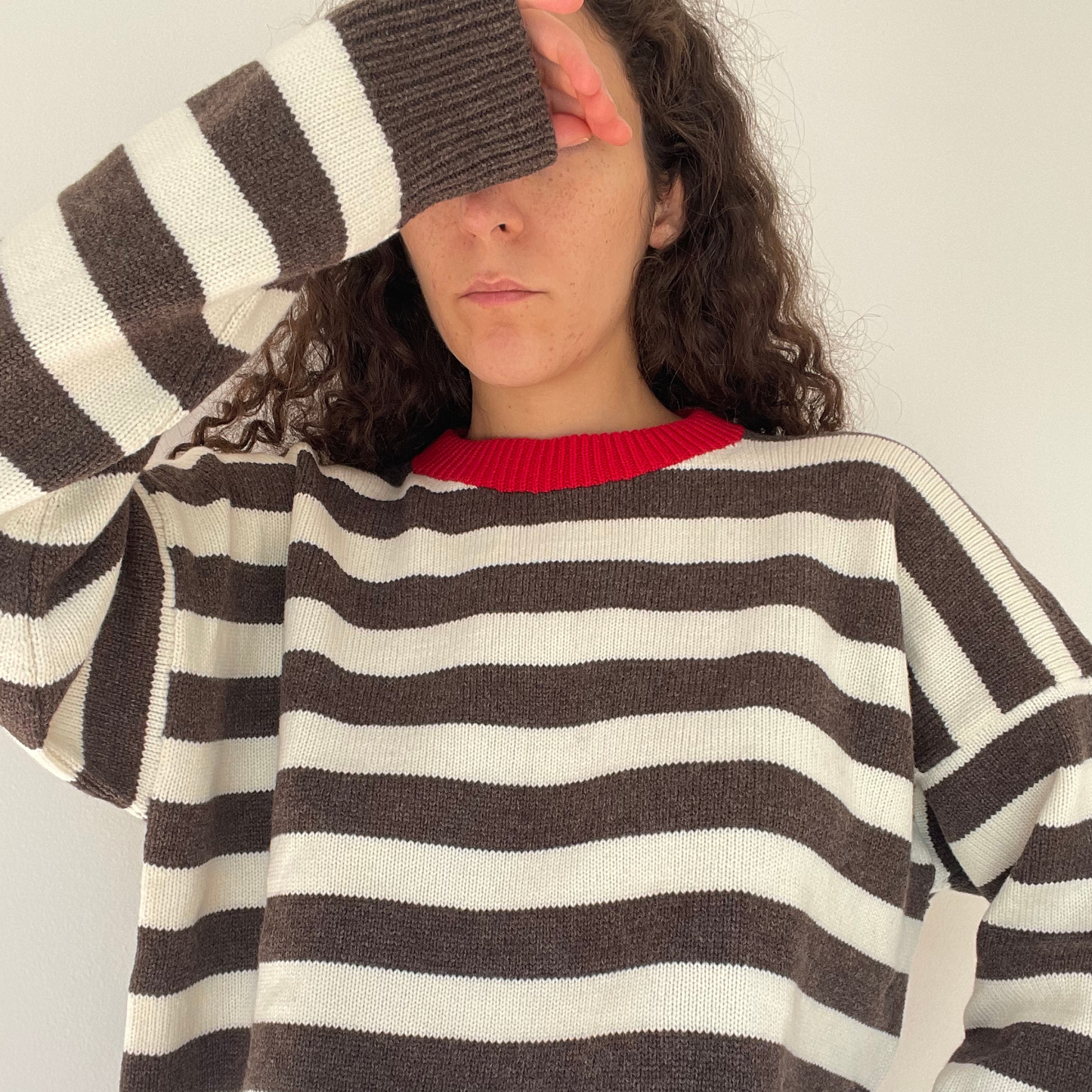 Person wearing a brown and white striped sweater with a red collar.
Striped sweater with a red collar on a white background.
givéh knitwear handmade by female artisans in iran using only natural and recycled fibres. contemporary knitwear for cool people. brown and cream striped unisex sweater with red crew neckline. 100% merino wool. fall 2025 collection.