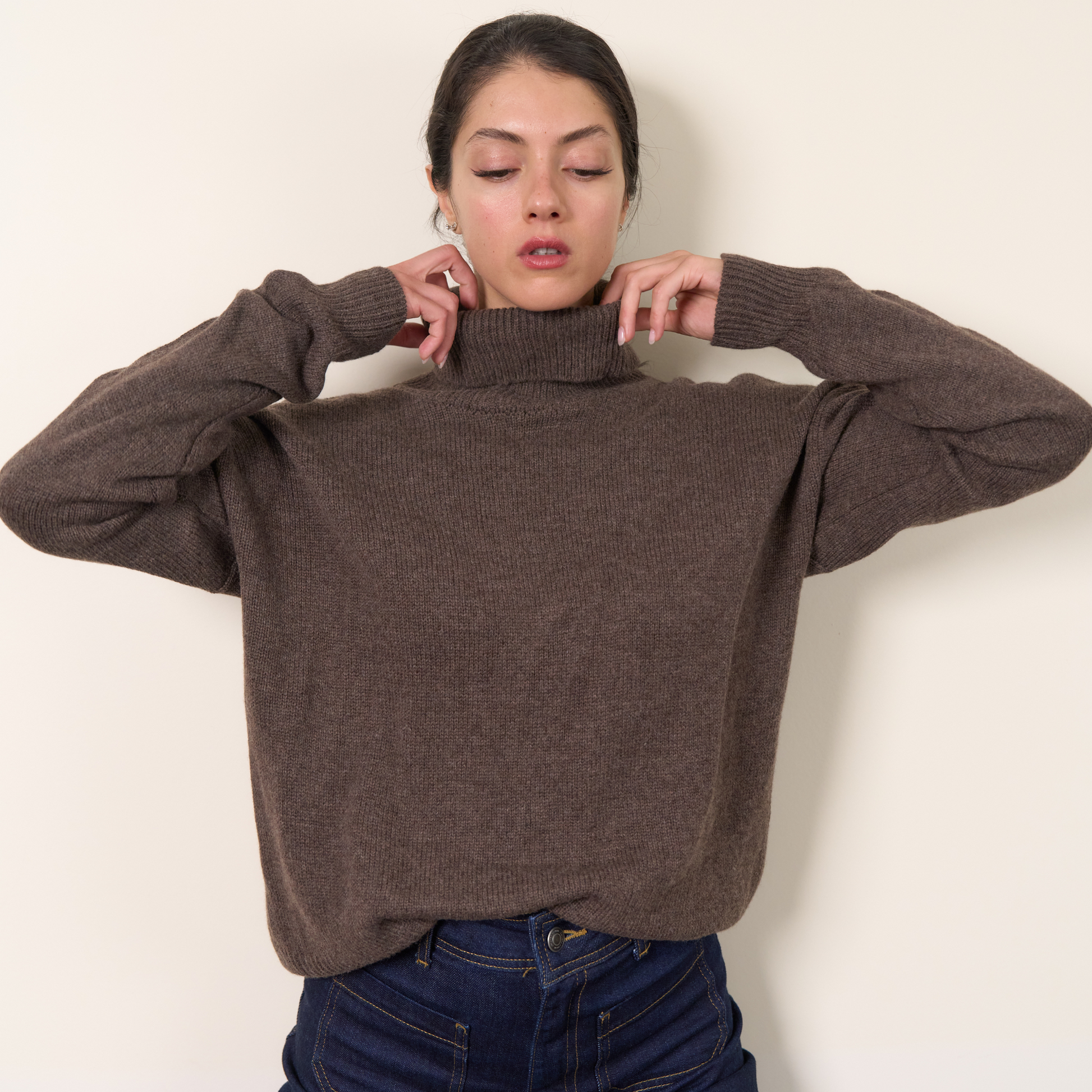 Woman wearing a brown sweater against a plain background.
givéh knitwear handmade by female artisans in iran using only natural and recycled fibres. contemporary knitwear for cool people. turtleneck sweater in brown. 100% merino wool. fall 2025 collection.