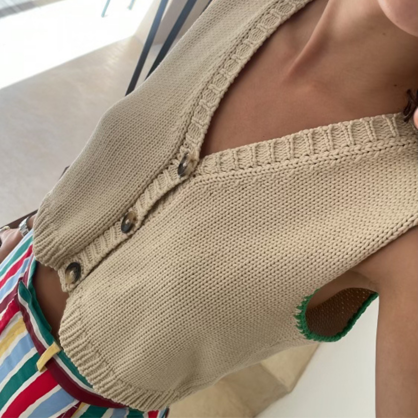 givéh knitwear handmade by female artisans in iran using only natural and recycled fibres. contemporary knitwear for cool people. cream vesty vest, cream and green knit vest with three natural horn buttons, made of cotton and recycled polyamide yarn, handcrocheted edges. spring summer 2025 collection.