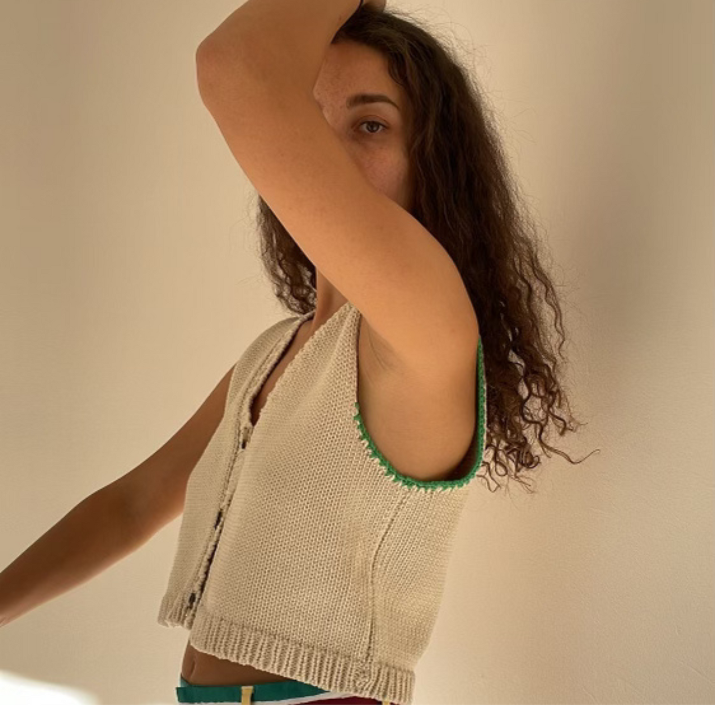 givéh knitwear handmade by female artisans in iran using only natural and recycled fibres. contemporary knitwear for cool people. cream vesty vest, cream and green knit vest with three natural horn buttons, made of cotton and recycled polyamide yarn, handcrocheted edges. spring summer 2025 collection.