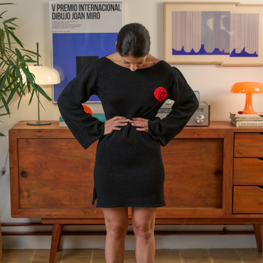 givéh knitwear handmade by female artisans in iran using only natural and recycled fibres. contemporary knitwear for cool people. black dress with red hand crocheted flower. made of merino wool. fall 2025 collection.