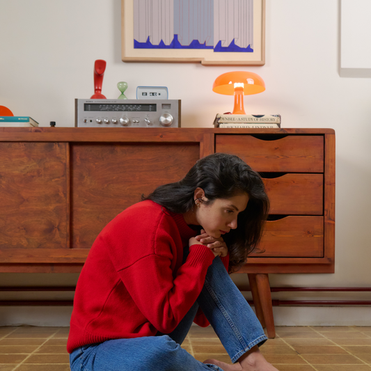 Woman in a red sweater sitting on the floor in front of a wooden cabinet with vintage decor.
givéh knitwear handmade by female artisans in iran using only natural and recycled fibres. contemporary knitwear for cool people. red unisex crewneck sweater. 100% merino wool. fall 2025 collection.