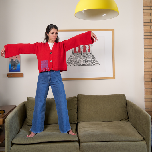 givéh knitwear handmade by female artisans in iran using only natural and recycled fibres. contemporary knitwear for cool people. red cardigan with red/purple gradient fringe pocket. 3 natural horn buttons. 100% merino wool. fall 2025 collection.