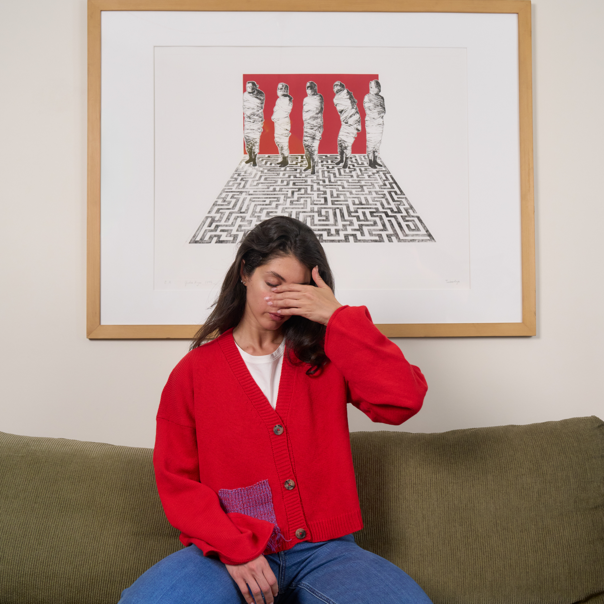 Woman in a red cardigan sitting on a couch with a framed artwork behind her.
givéh knitwear handmade by female artisans in iran using only natural and recycled fibres. contemporary knitwear for cool people. red cardigan with red/purple gradient fringe pocket. 3 natural horn buttons. 100% merino wool. fall 2025 collection.