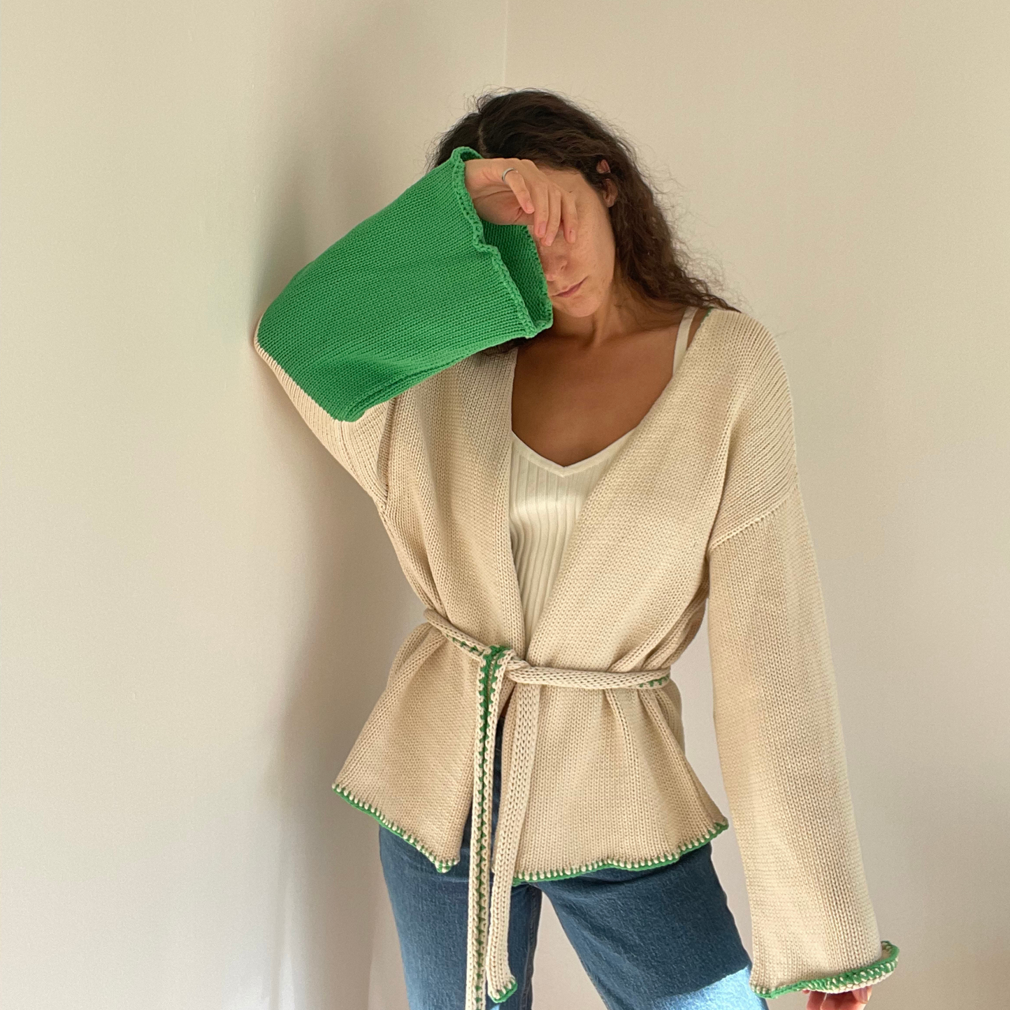 givéh knitwear handmade by female artisans in iran using only natural and recycled fibres. contemporary knitwear for cool people. cream the cardi, cream and green knit cardigan with belt made of cotton and recycled polyamide yarn. spring summer 2025 collection.
