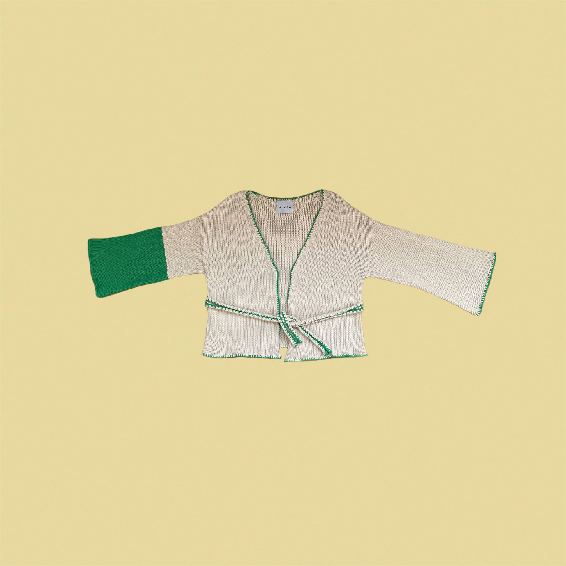 givéh knitwear handmade by female artisans in iran using only natural and recycled fibres. contemporary knitwear for cool people. cream the cardi, cream and green knit cardigan with belt made of cotton and recycled polyamide yarn. spring summer 2025 collection.